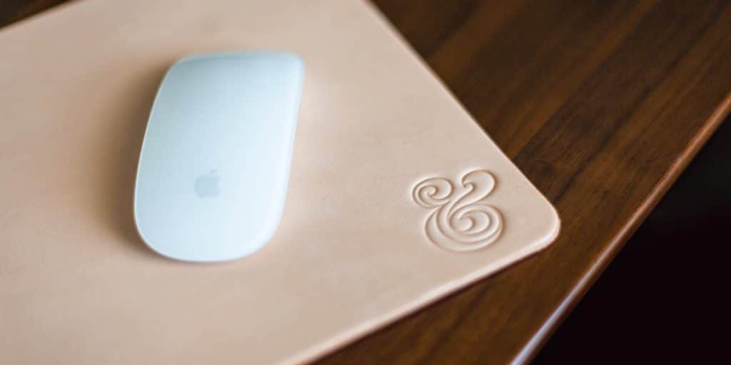A computer mouse sitting on a mouse pad, on top of a wood desk.