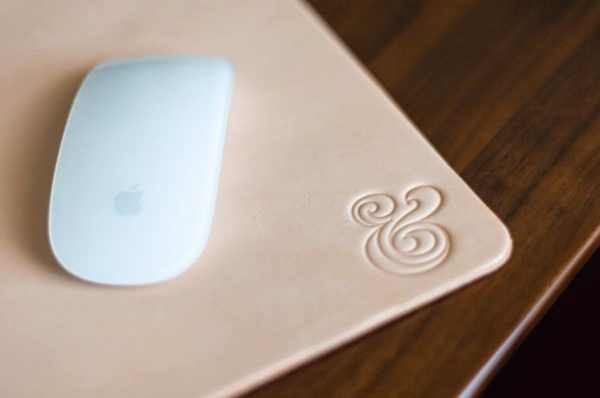 A computer mouse sitting on a mouse pad, on top of a wood desk.