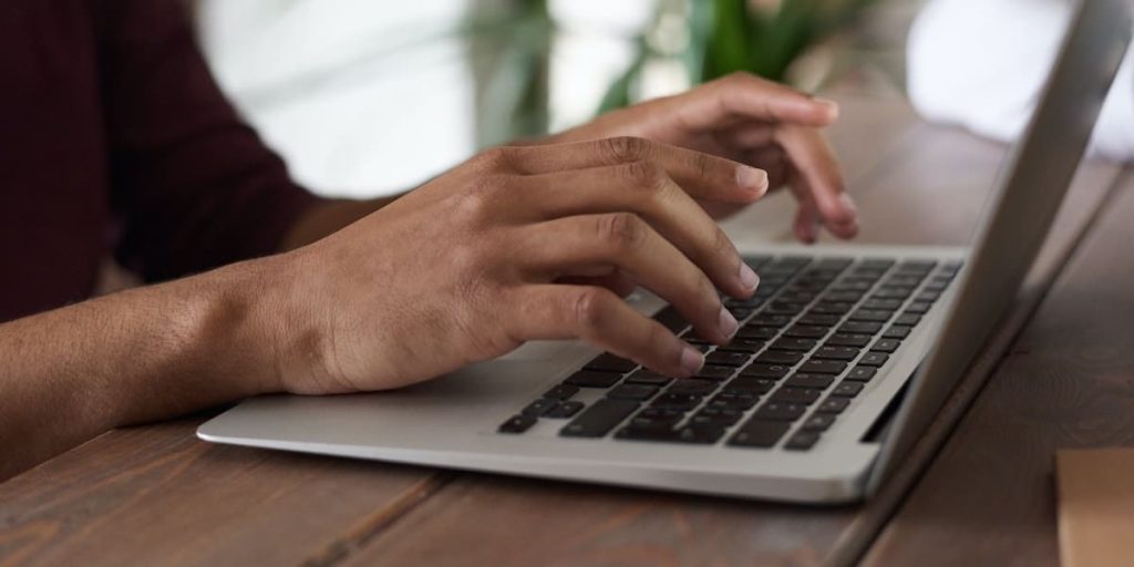 Person typing on a laptop keyboard.