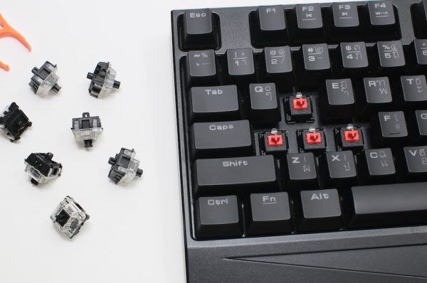 Mechanical keyboard with WASD keycaps missing, next to switches and a puller.